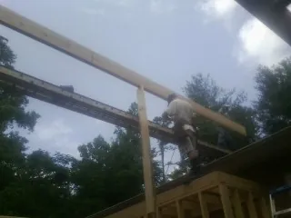 Carpenter setting a ridge beam over a new addition frame — Ice Dam Removal by Roofing Brothers in Primghar