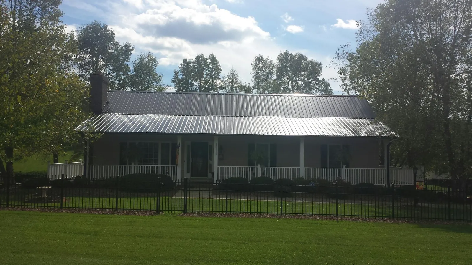 Gray metal roof on a brick ranch with a full width front porch — Gutter Guard Installation work by our crew in Primghar
