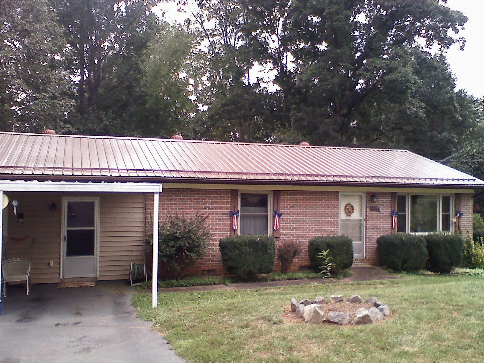 Bronze metal roof and carport on a brick ranch home — Roof Repair work by our crew in Primghar