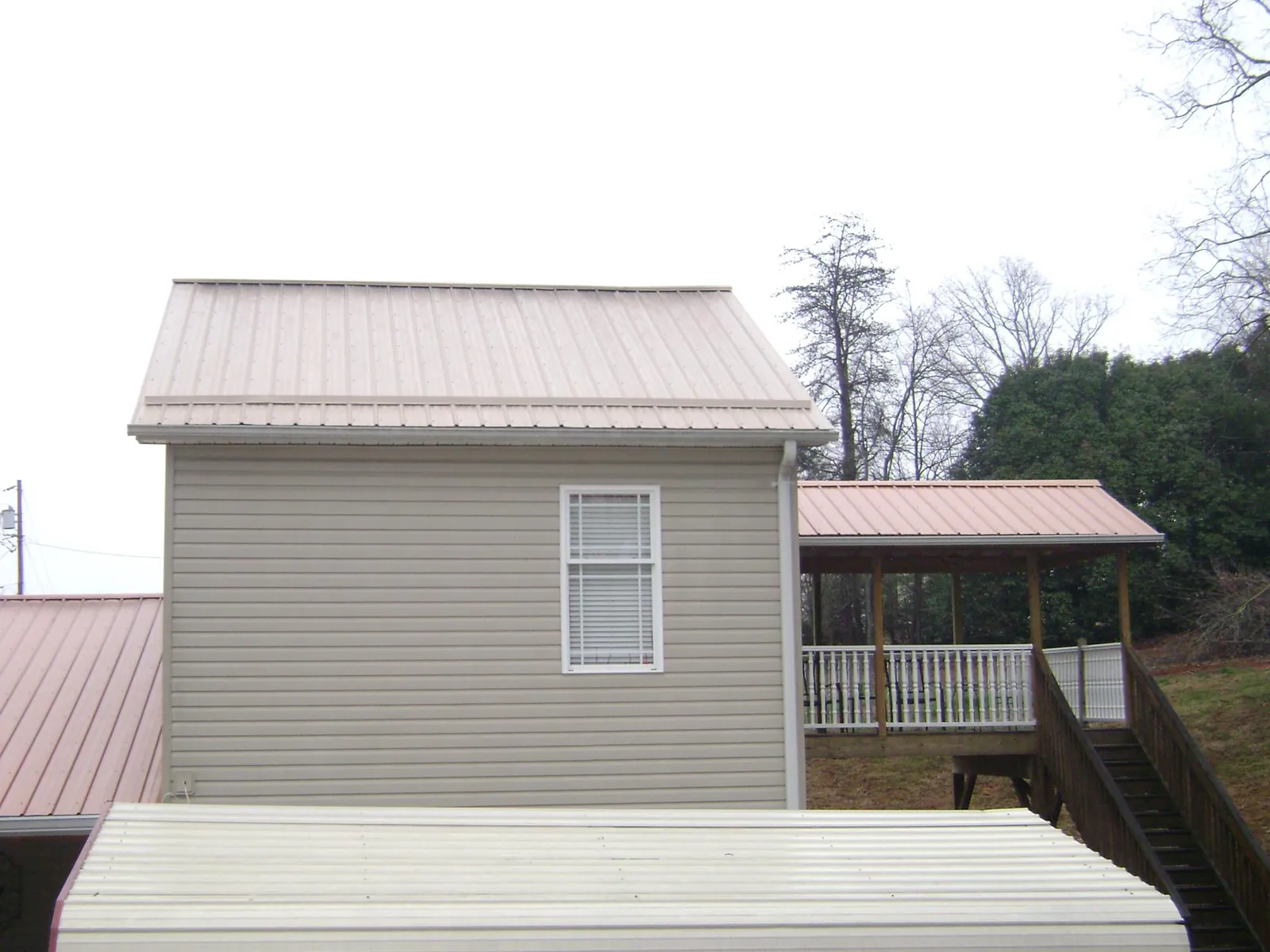Tan metal roofs on a two story addition and attached porch, from a Roof Replacement job in Primghar