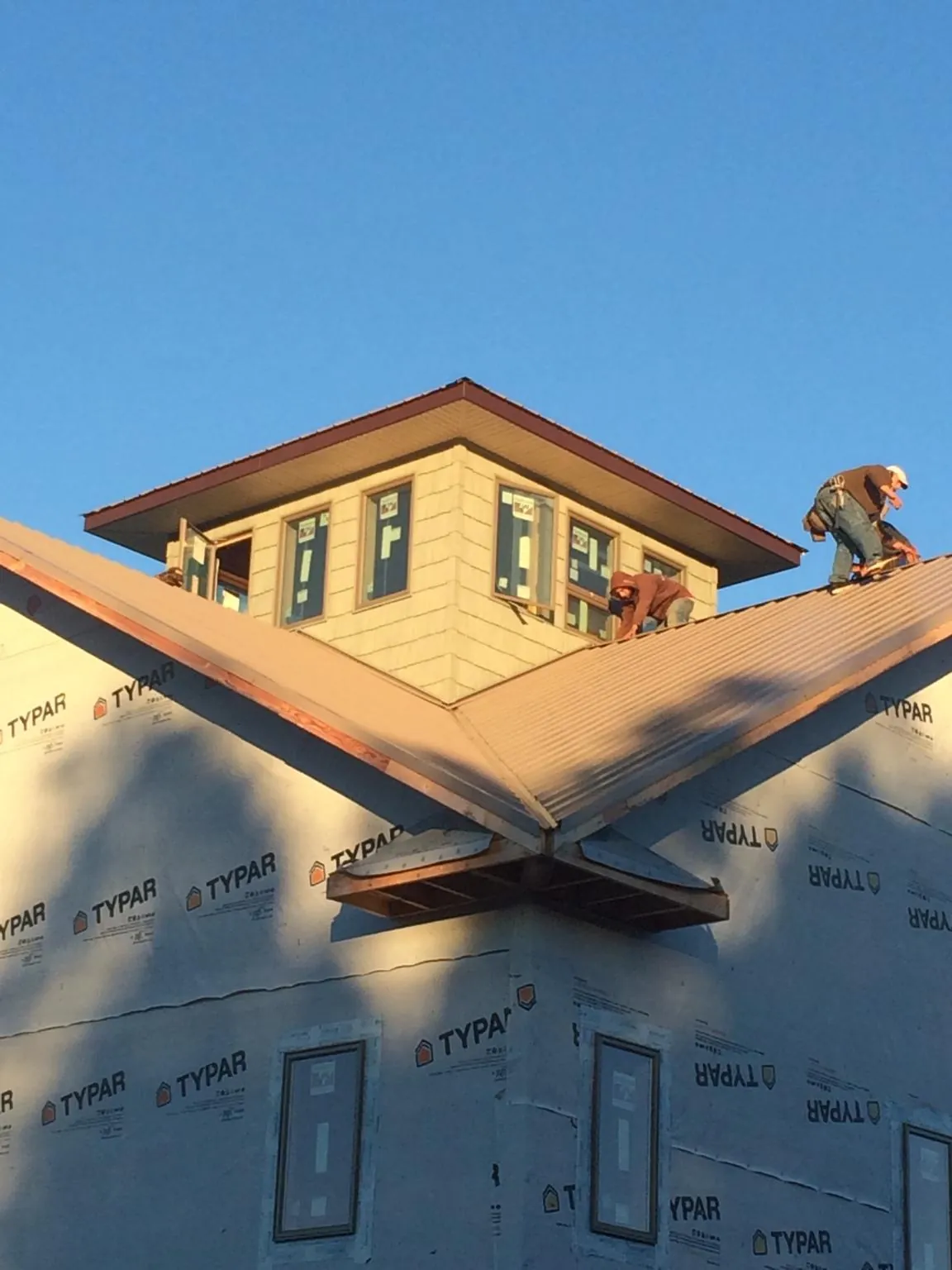 Roofers working around a rooftop cupola on a new metal roof at sunset — Roof Waterproofing in Primghar by Roofing Brothers